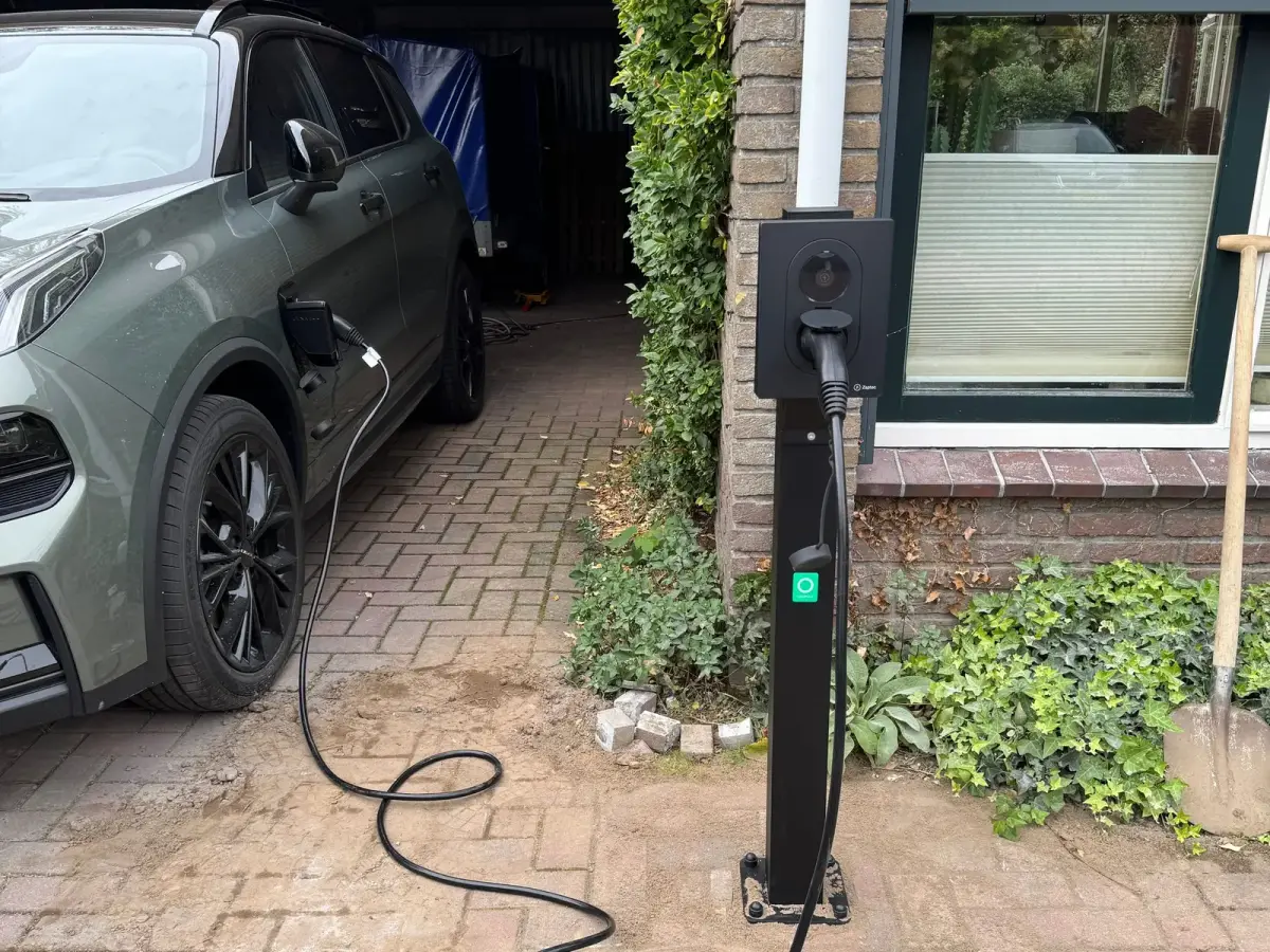 Laadpaal op een paal naast de oprit, met de laadkabel in de auto